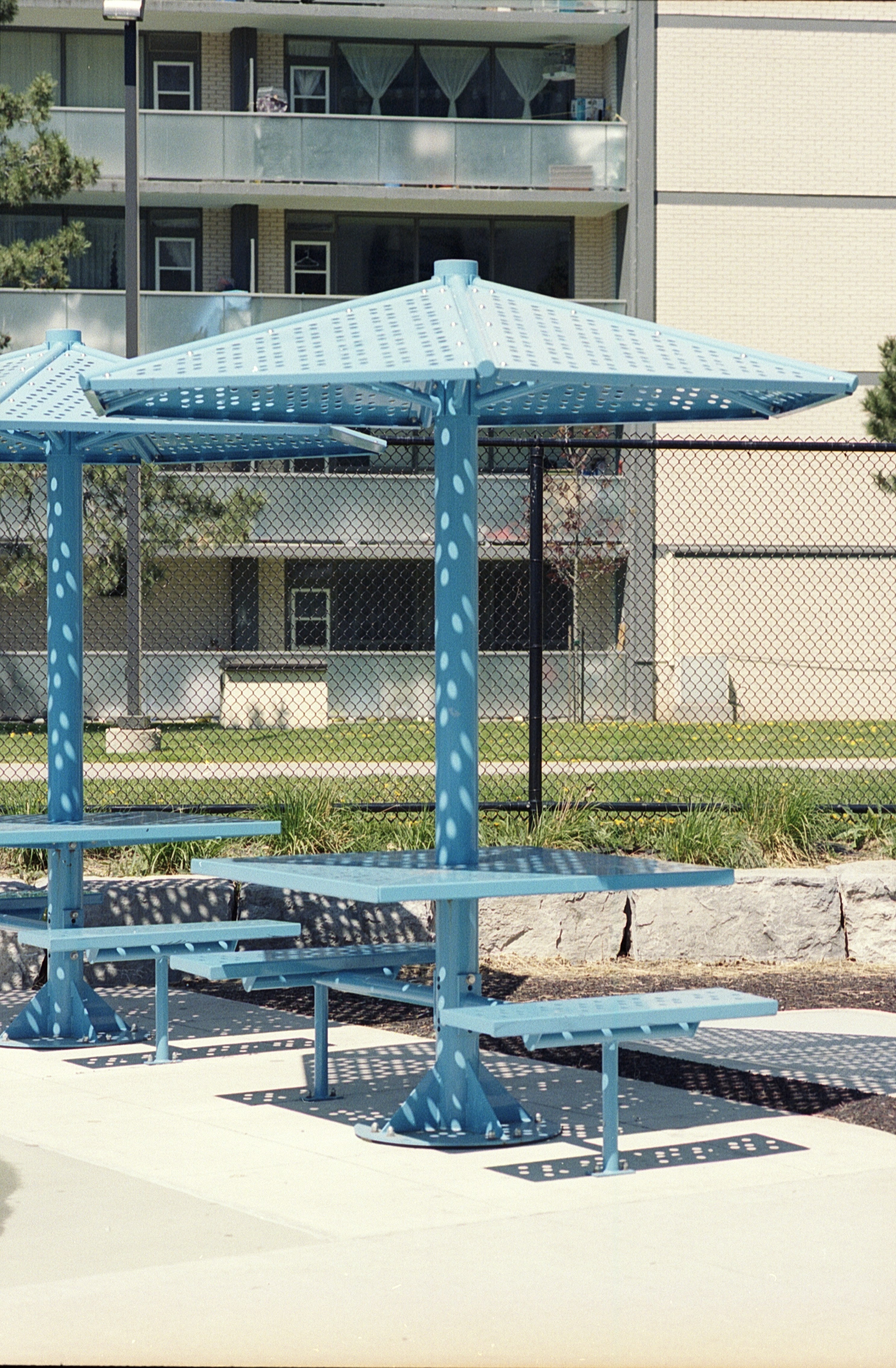 a couple of blue benches sitting under a blue umbrella