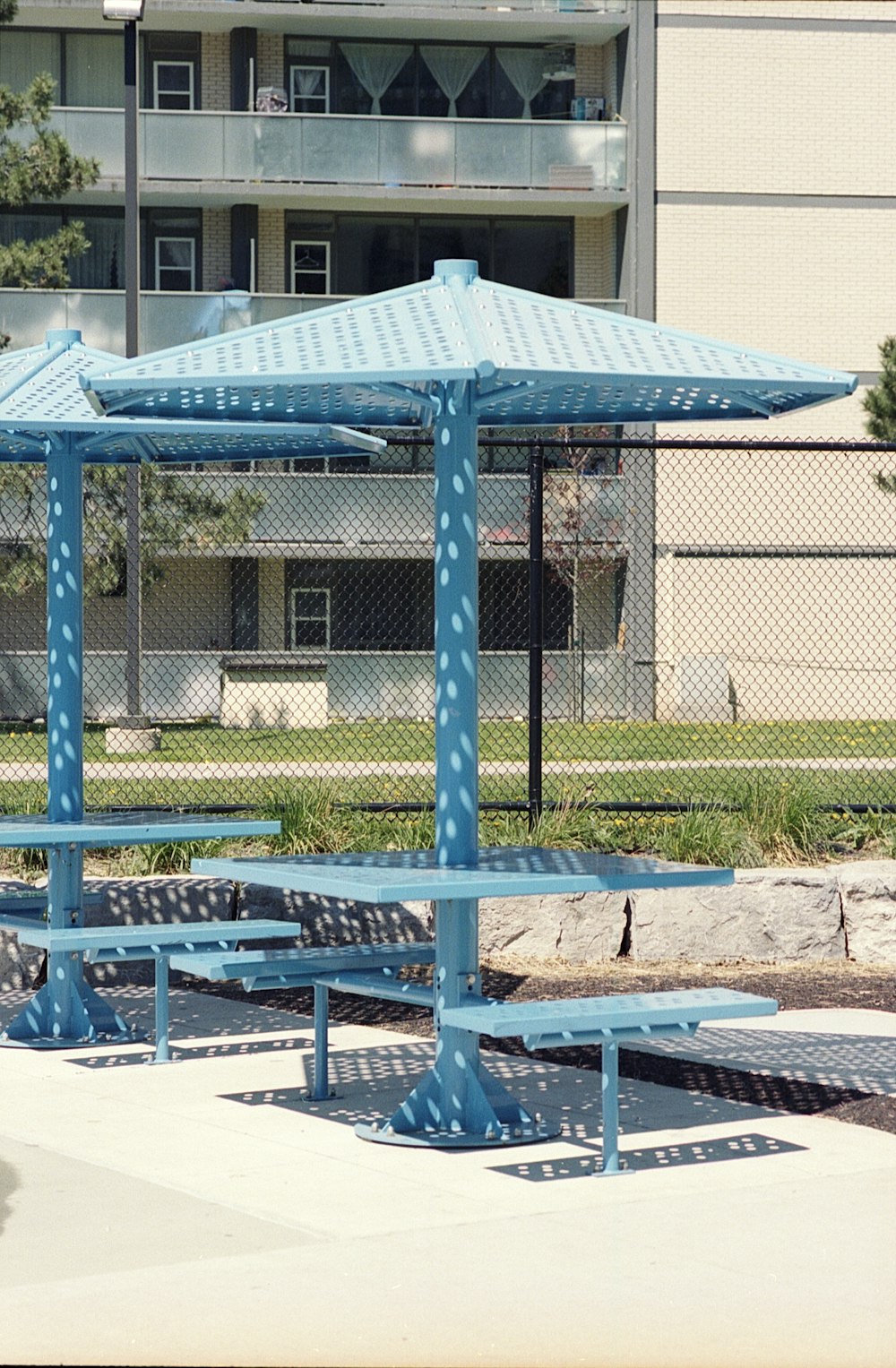 a couple of blue benches sitting under a blue umbrella