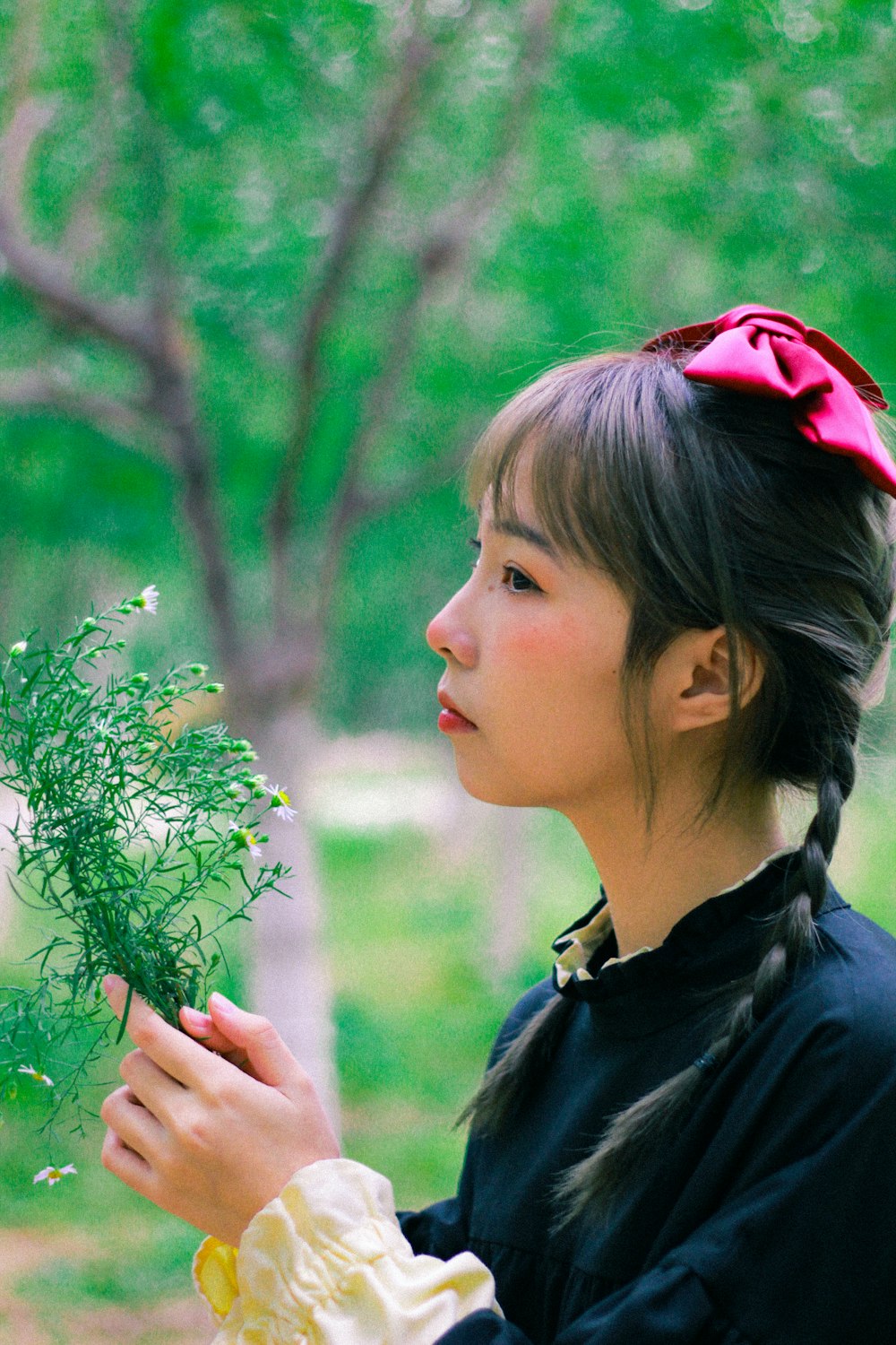 a woman in a black dress holding a green plant