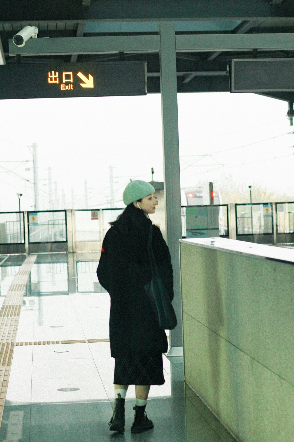 a woman is waiting at a train station