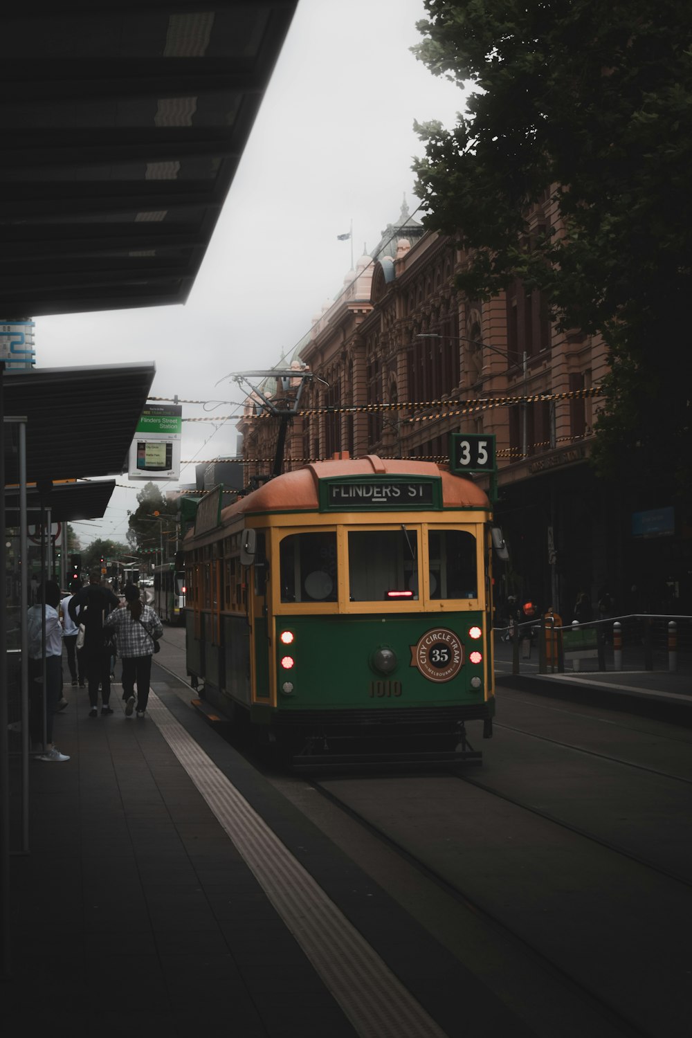 a green and yellow trolley on a city street