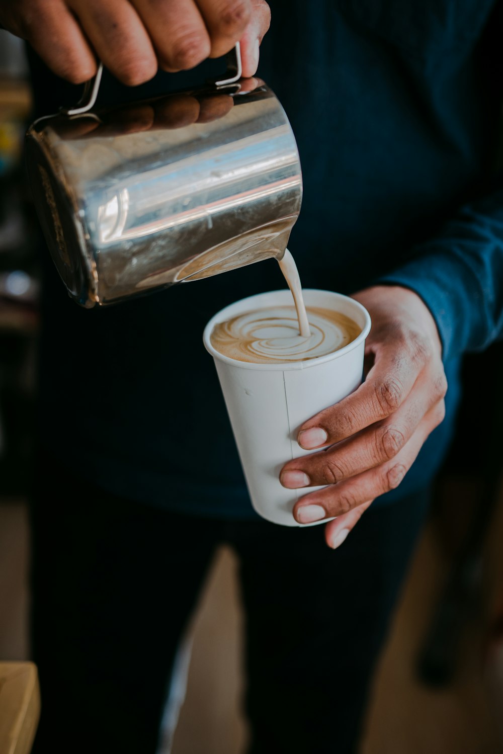 person pouring milk on white ceramic mug