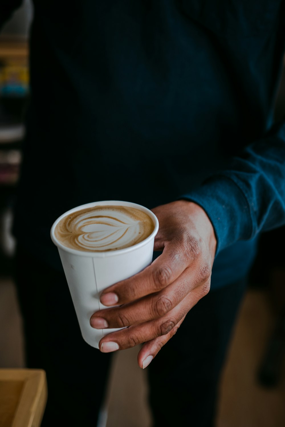 a person holding a cup of coffee in their hand