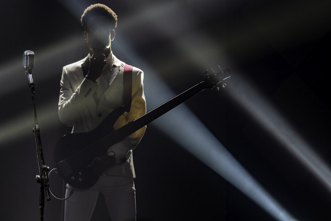 a man holding a guitar in front of a microphone, Think in music...