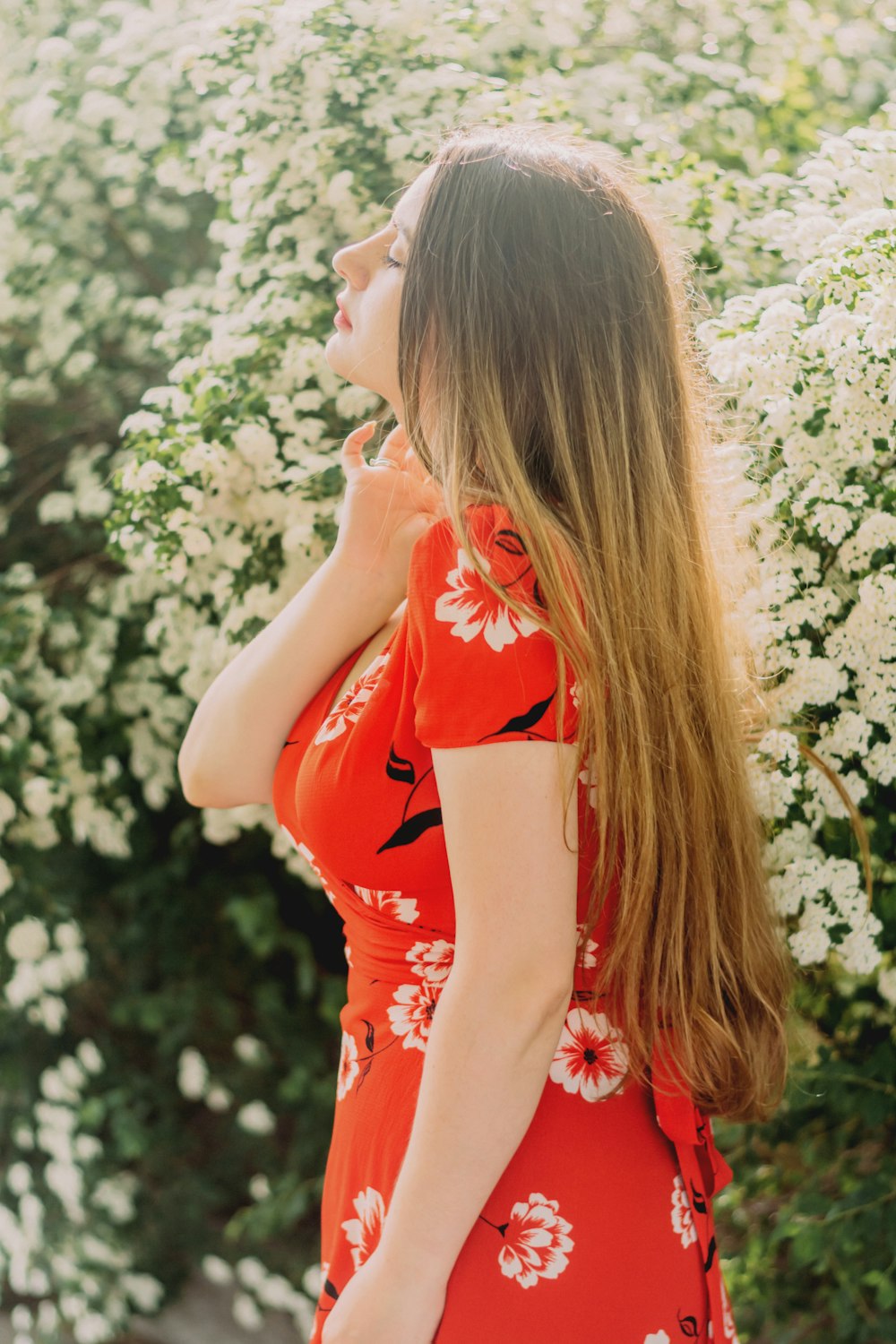 a woman in a red dress standing in front of white flowers