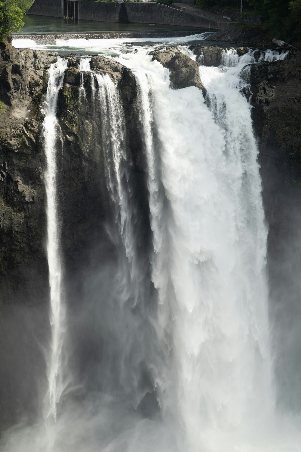 a large waterfall with a bridge in the background