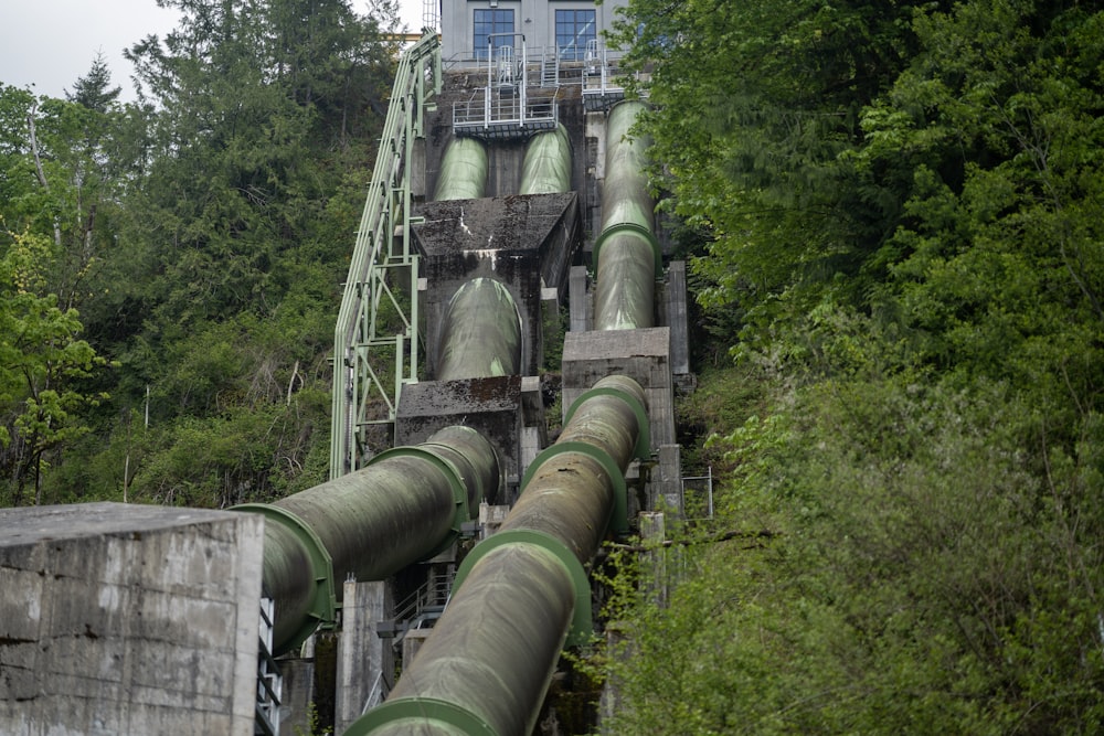 a large pipe going down a hill with trees in the background