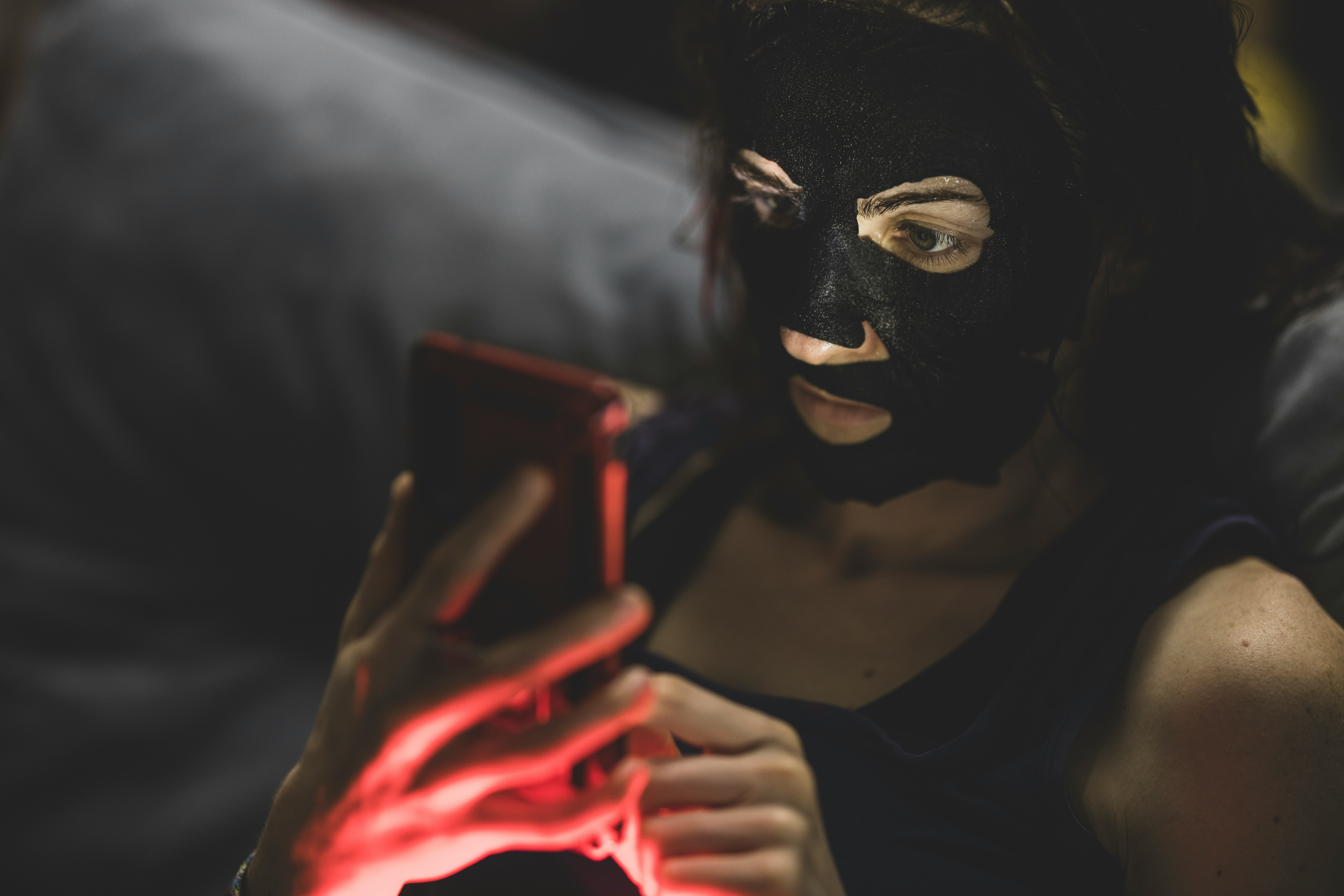 woman in black mask holding red smartphone