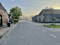A peaceful country road lined with trees and farmhouses, illustrating the communities we help build.
