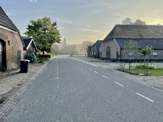 A peaceful country road lined with trees and farmhouses, illustrating the communities we help build.