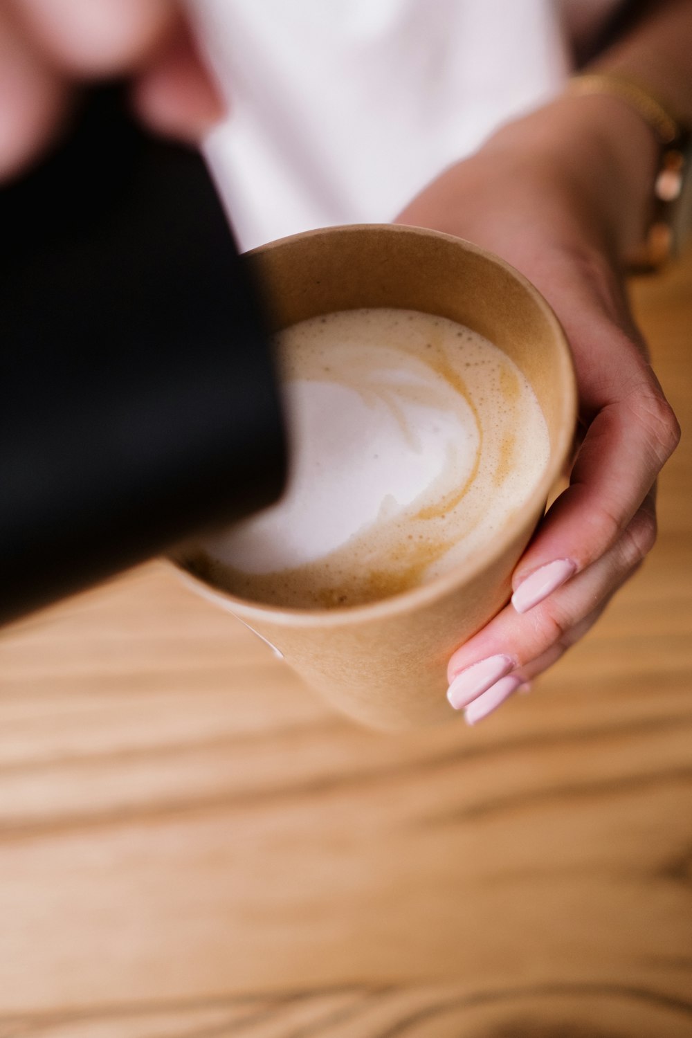 person holding white ceramic mug with brown liquid