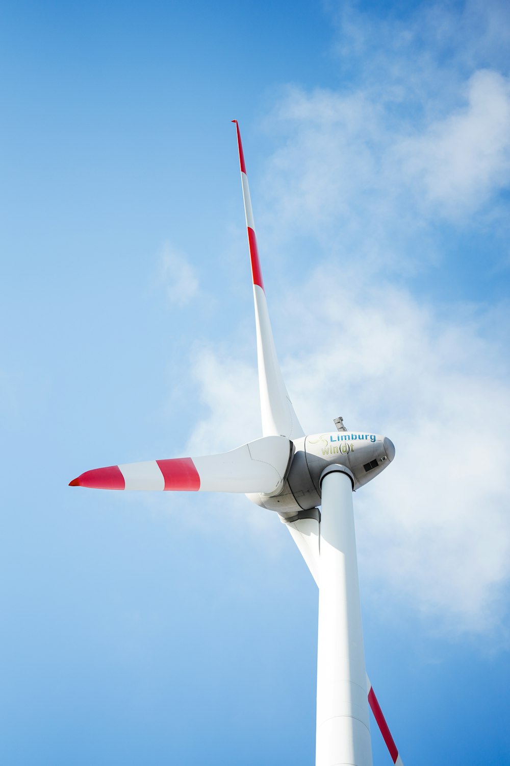 a white and red wind turbine against a blue sky