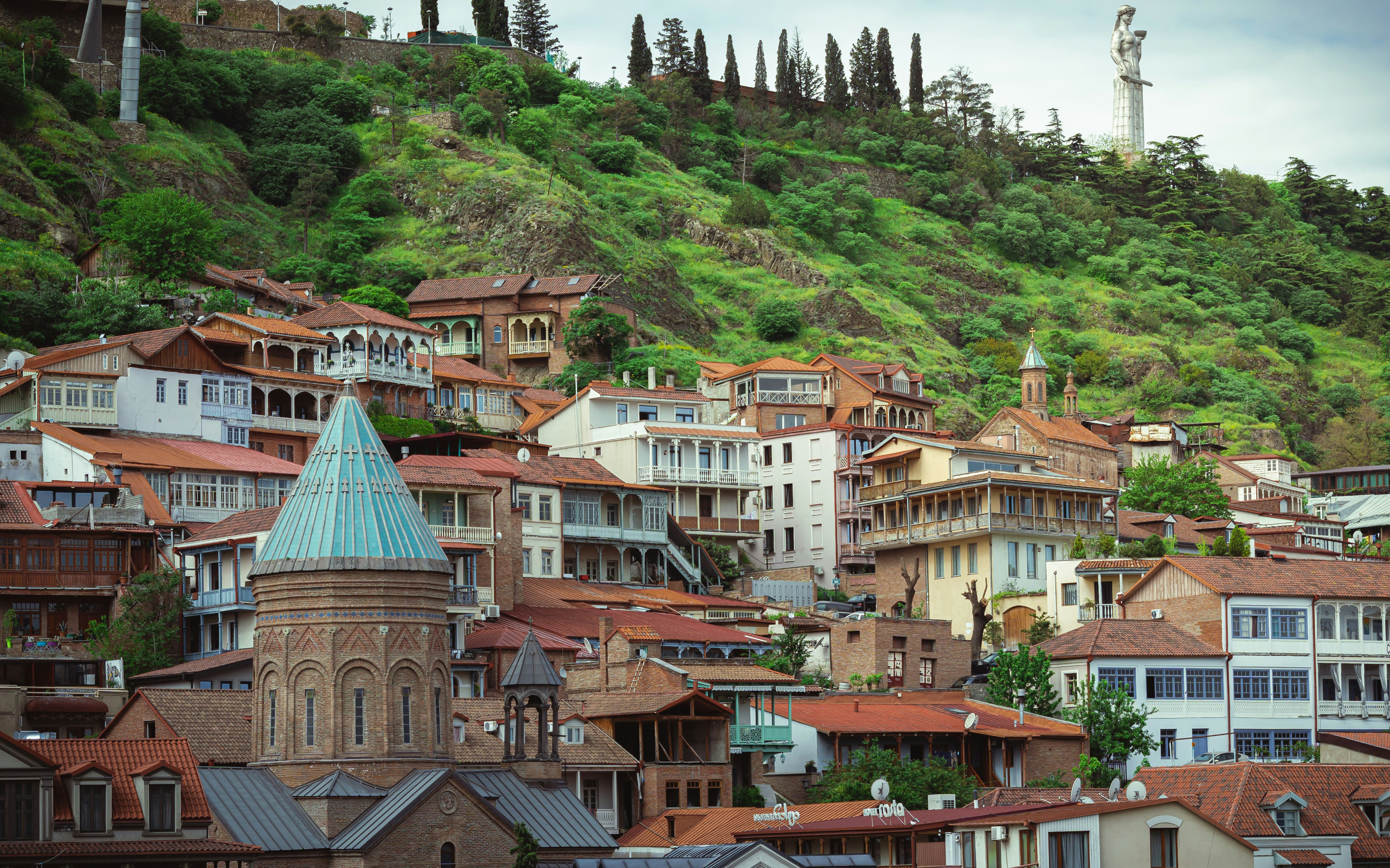 white and brown concrete houses near green mountain during daytime