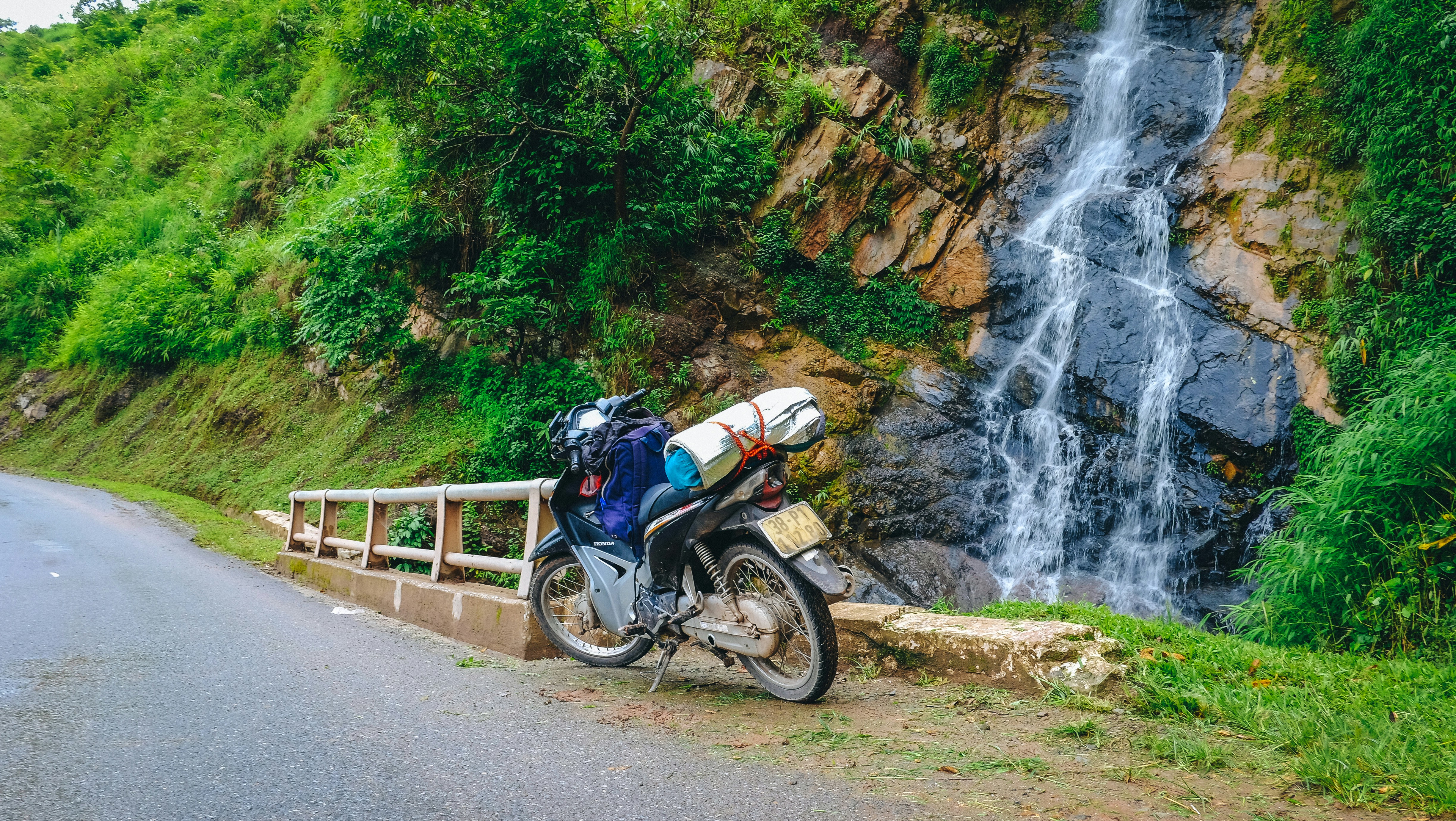 a motorcycle parked on the side of a road next to a waterfall