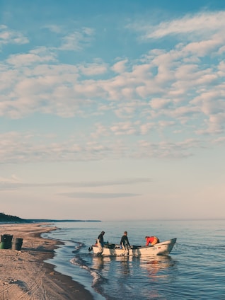 two people in a small boat on the beach