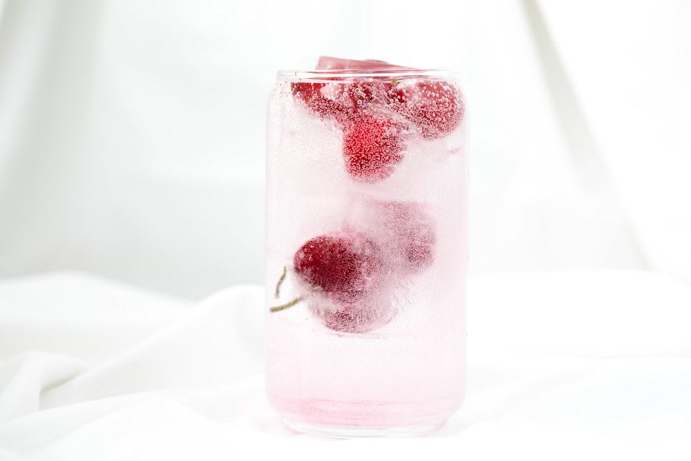 a glass filled with ice and two cherries