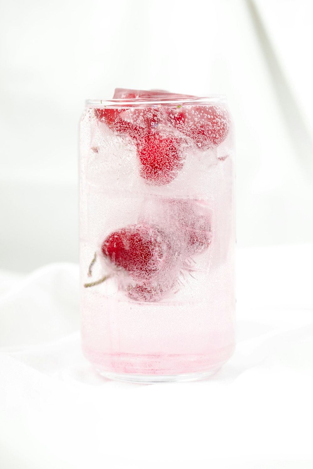 a glass of ice with raspberries in it