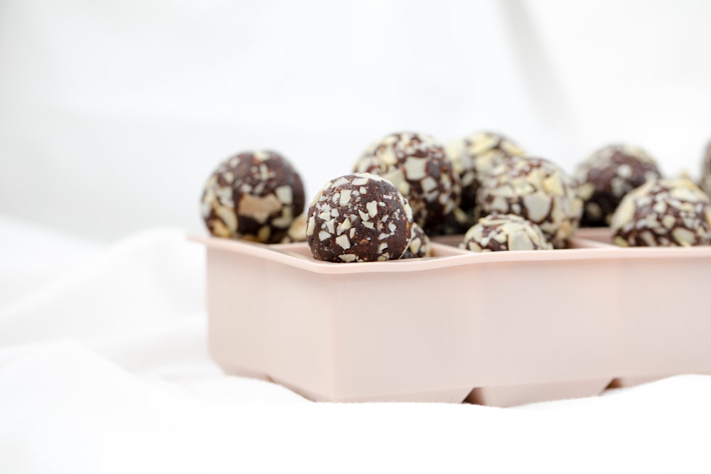 a pink tray filled with chocolate covered donuts