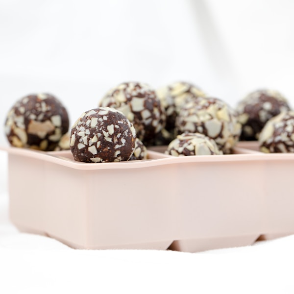 a pink tray filled with chocolate covered donuts