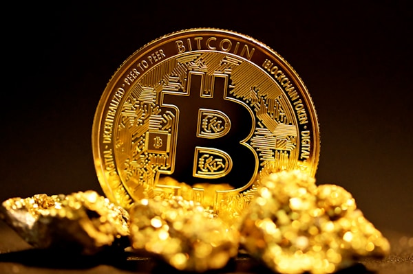 A gold Bitcoin coin standing among rough gold nuggets against a dark background