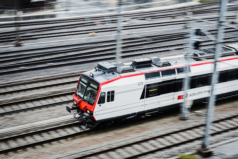 Ein weiß-roter Zug fährt die Bahngleise hinunter
