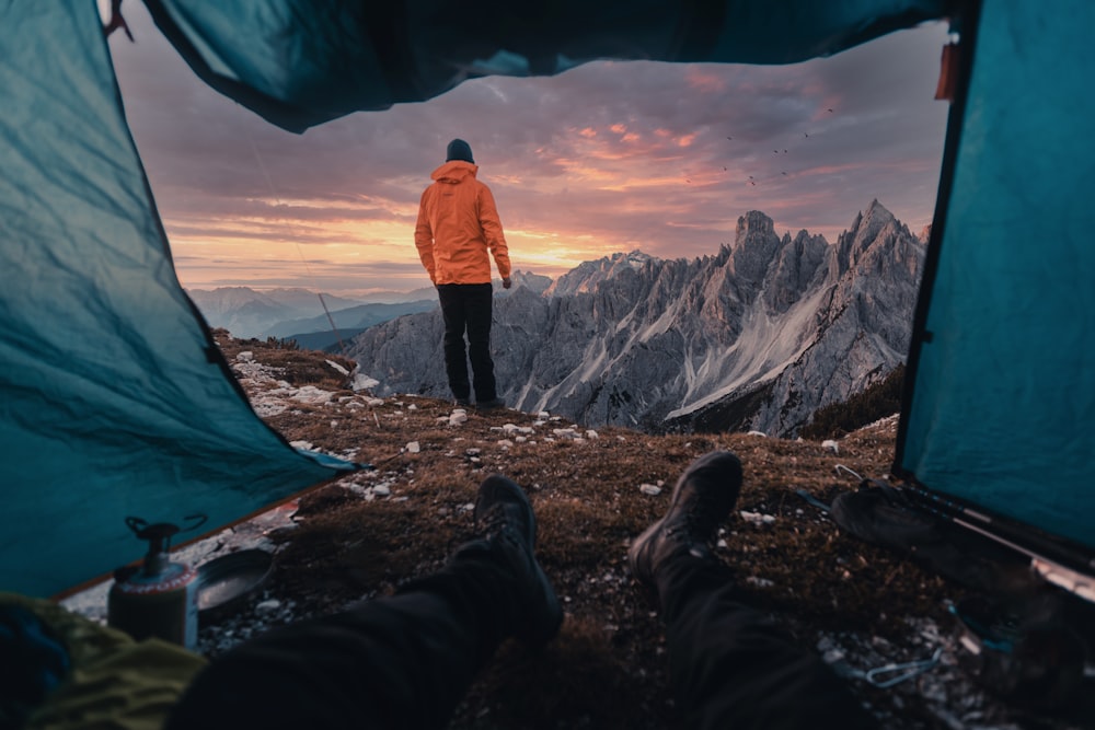 a man standing in a tent looking out at the mountains