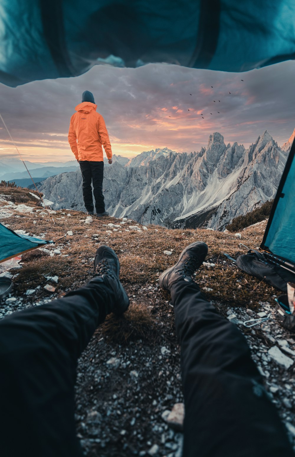 a man standing on top of a mountain next to a tent