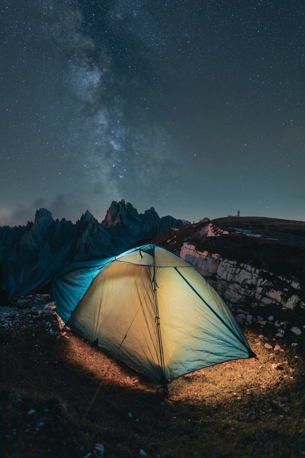 a tent pitched up in the mountains under a night sky