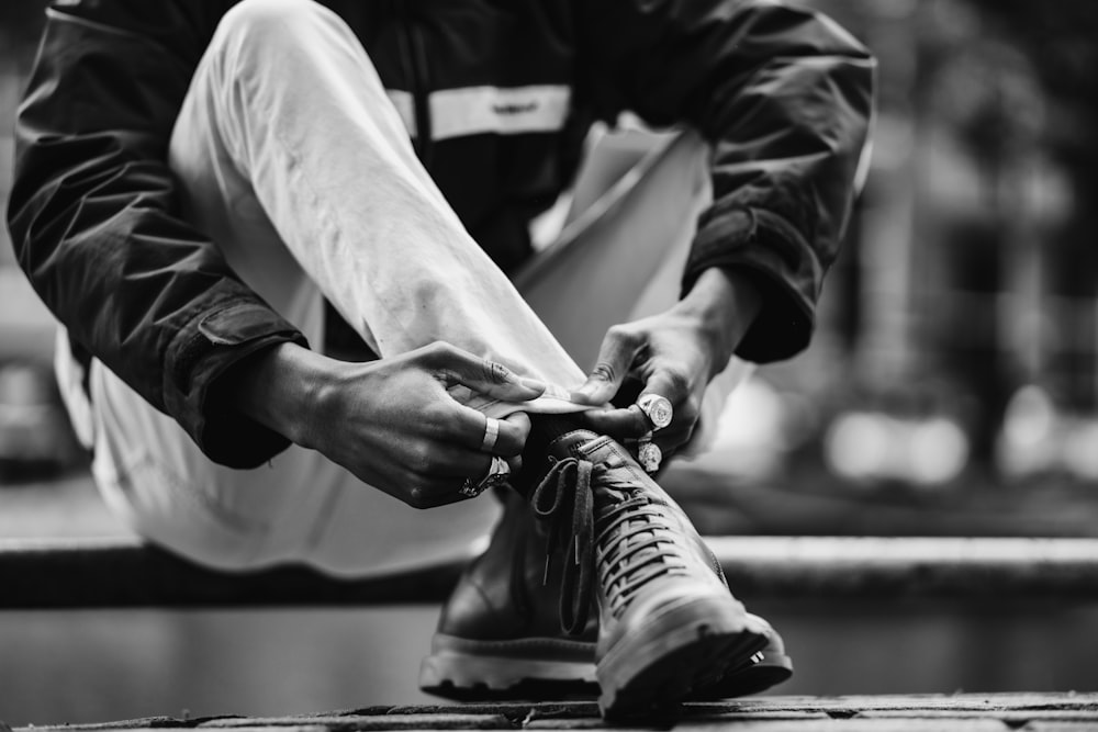 a black and white photo of a man tying his shoes