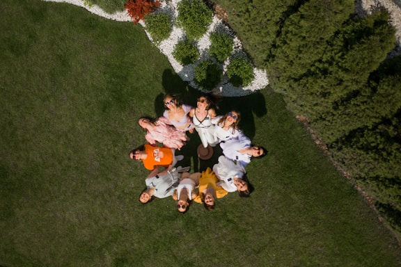 a group of people standing in a circle in the grass