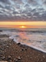 the sun is setting over the ocean on the beach