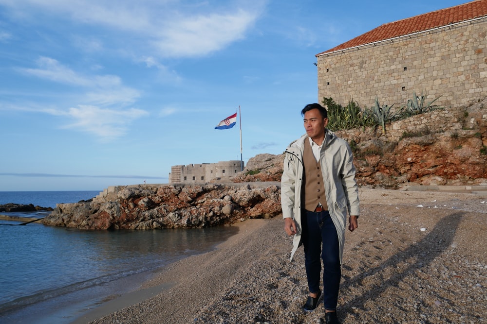 a man standing on a beach next to a body of water