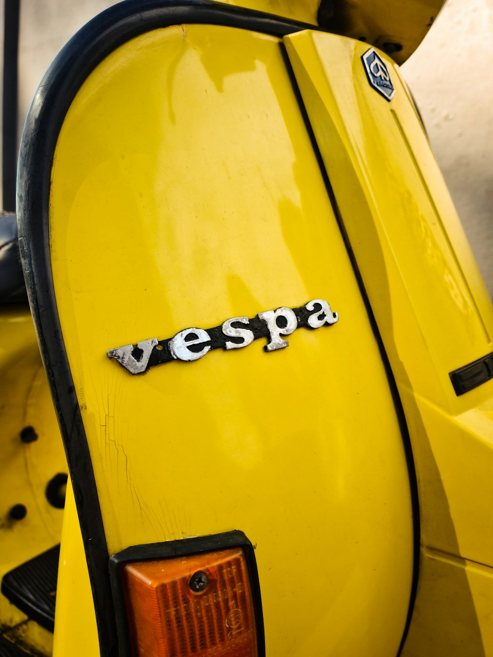 a yellow vespa scooter with the word vespa on it