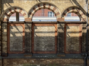 a brick building with arched windows and a bench in front of it