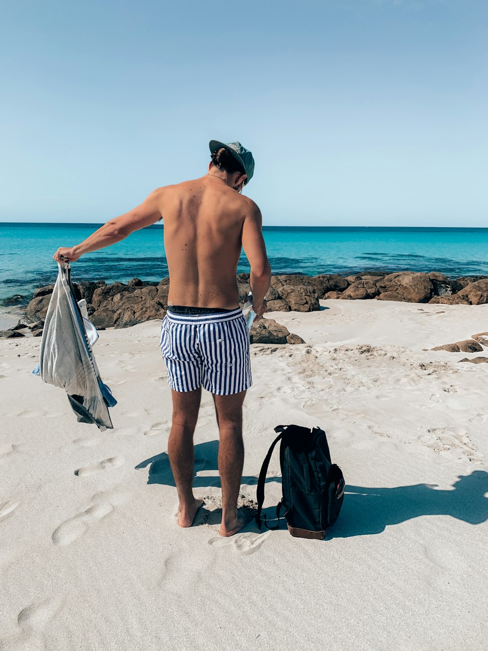 Un uomo in piedi su una spiaggia accanto a una borsa