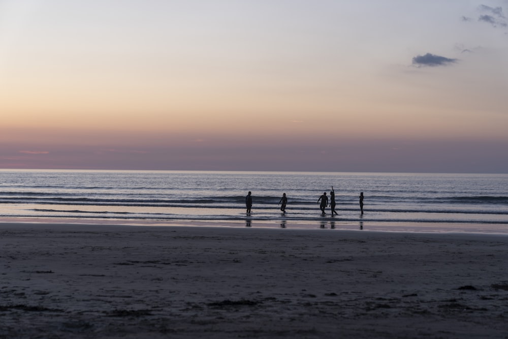 a group of people standing on top of a sandy beach