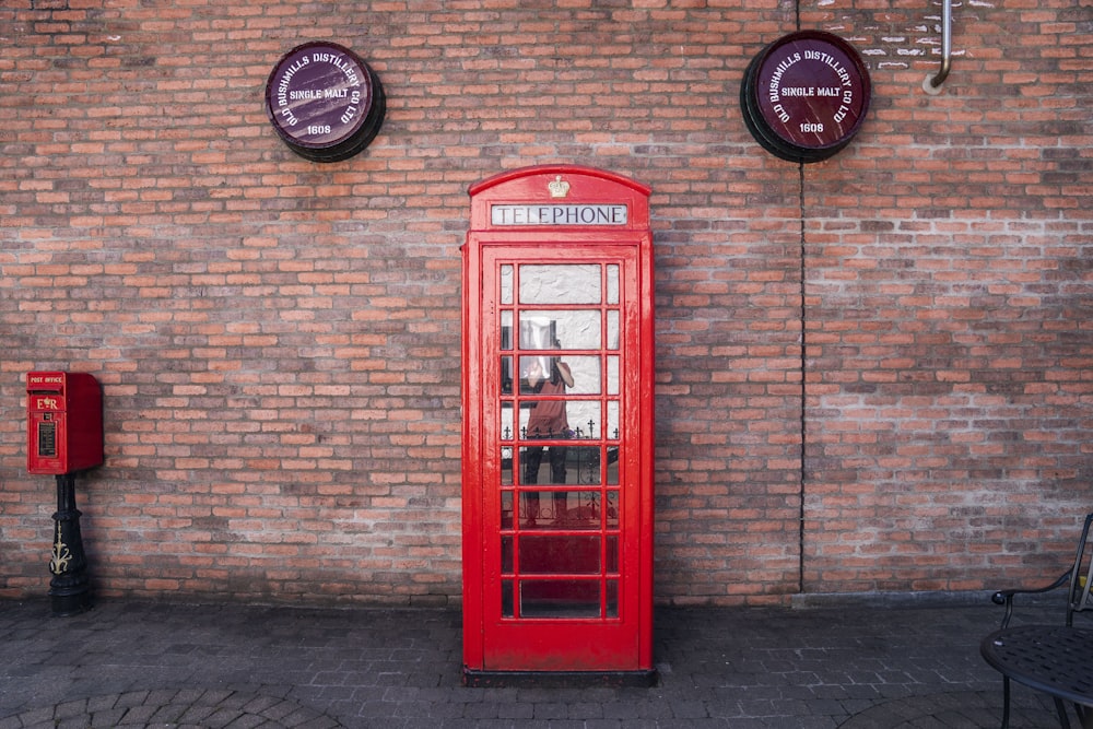 a red phone booth in front of a brick wall