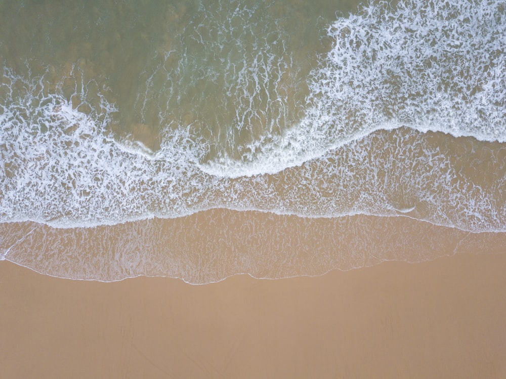 an aerial view of a beach with waves coming in