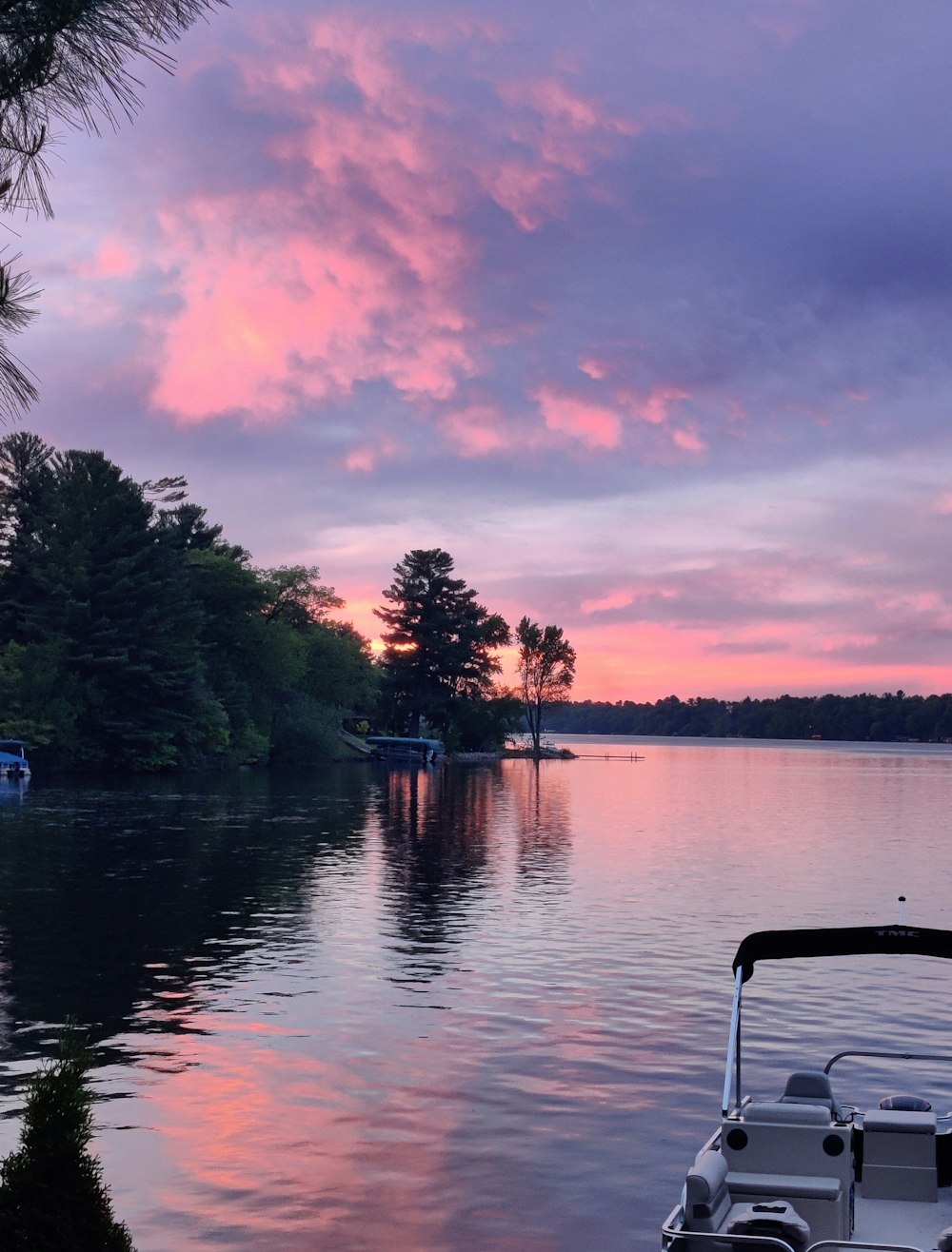 a boat sitting on top of a lake under a cloudy sky