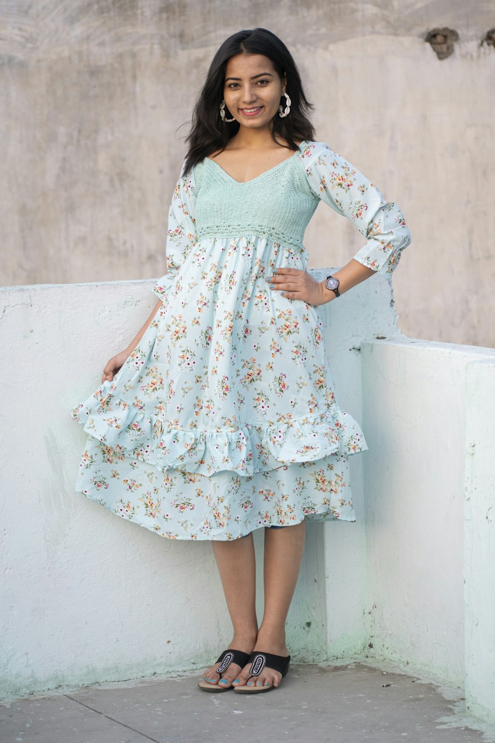 a woman standing on a ledge wearing a dress