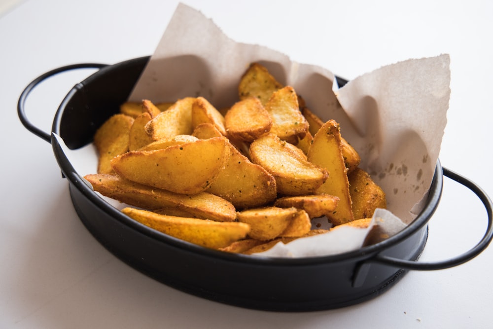 a black pan filled with potatoes on top of a table