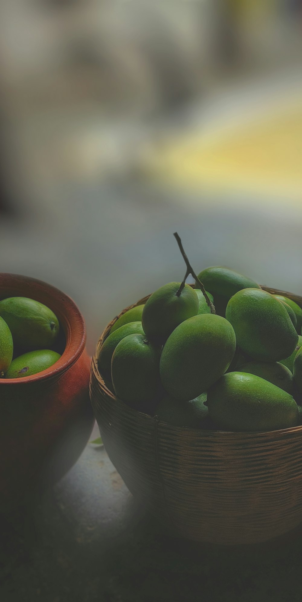 a wooden bowl filled with green apples next to a bowl of green apples