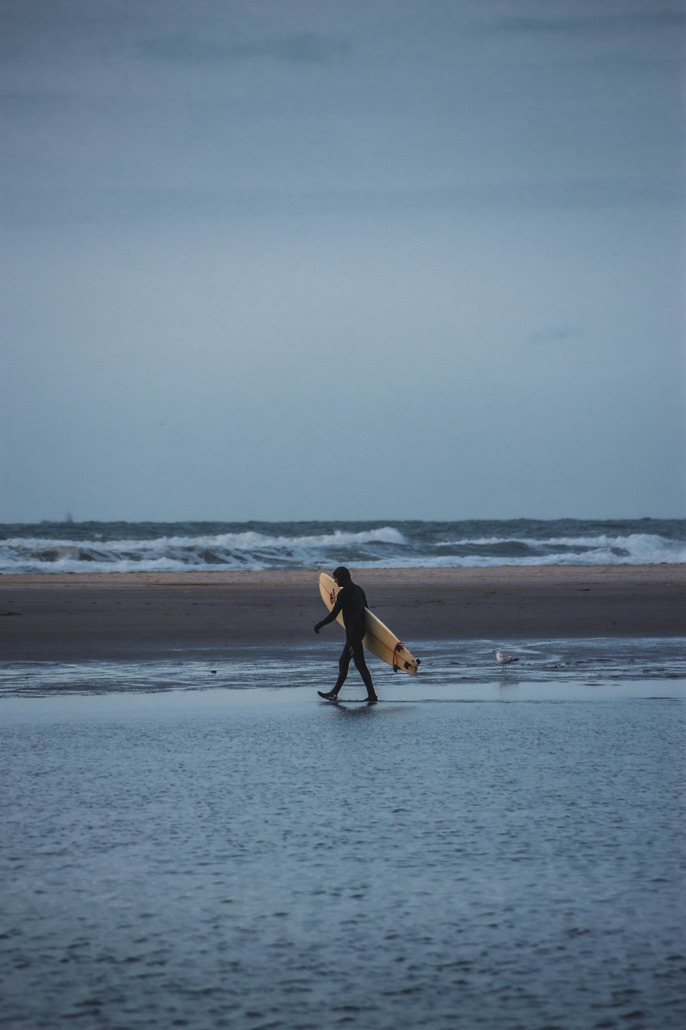 a man carrying a surfboard across a wet beach