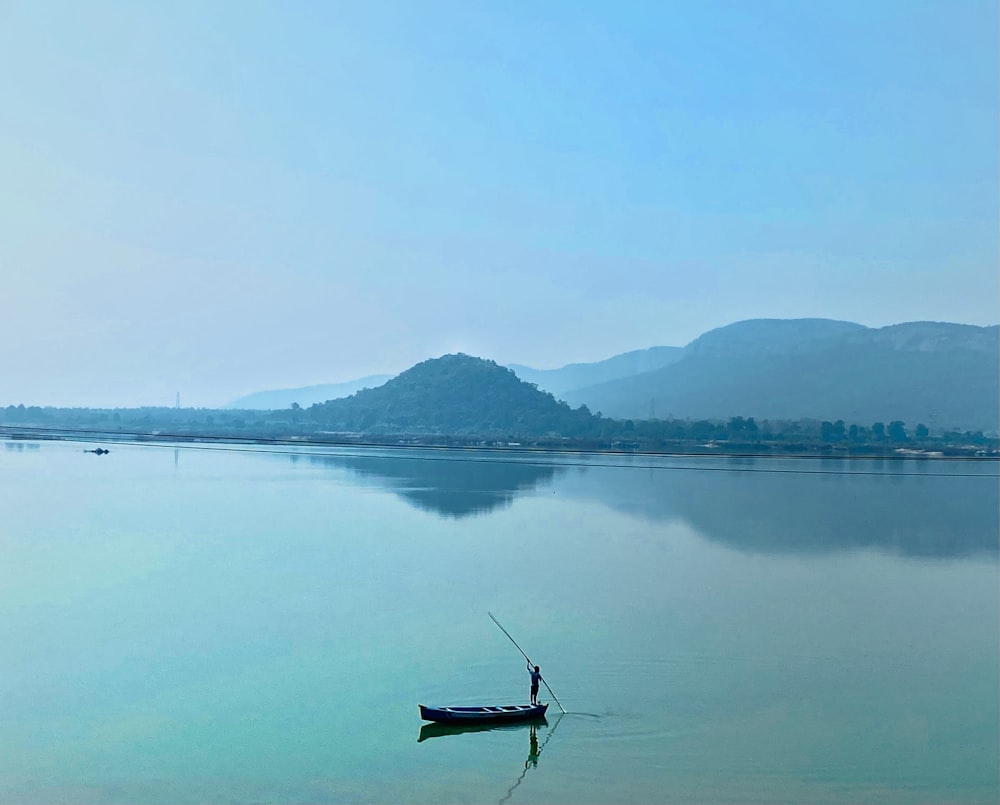 a man standing on a boat in the middle of a lake