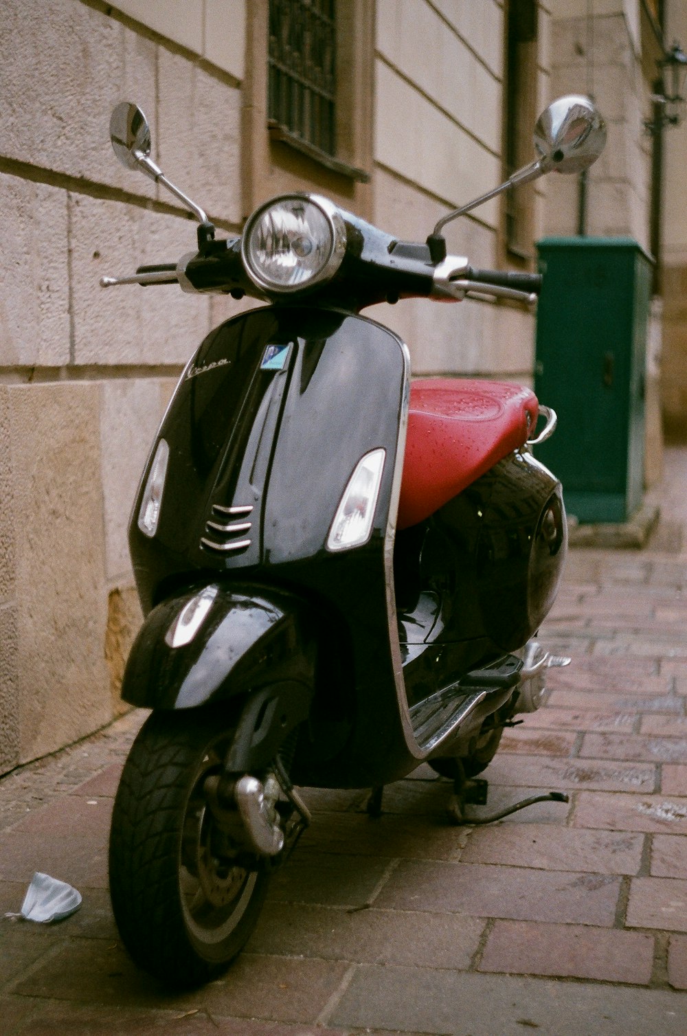 red and black motorcycle parked beside brown concrete wall