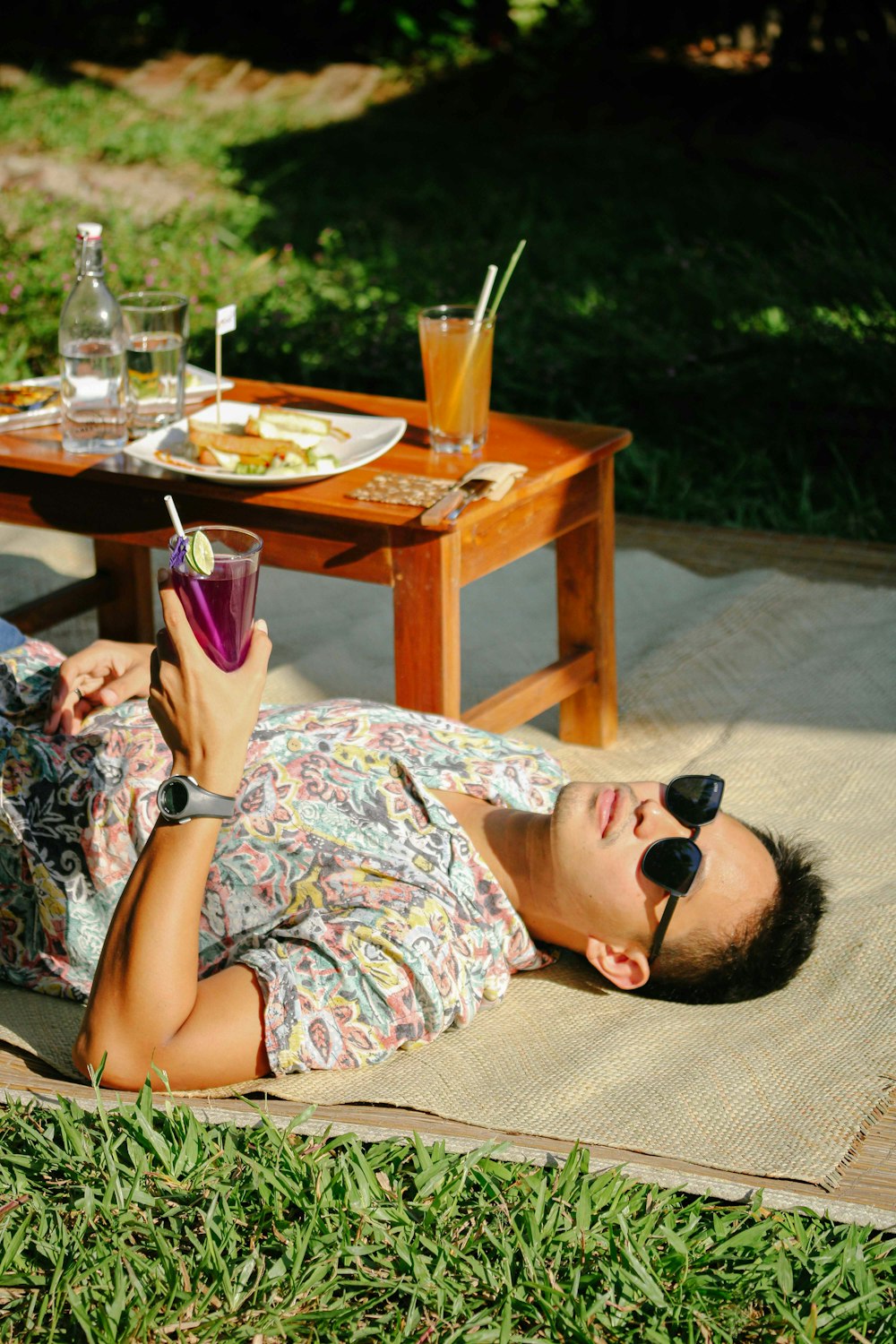 a woman laying on a mat with a drink in her hand