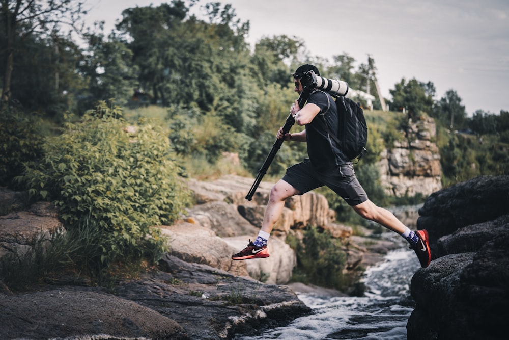 a man with a baseball bat jumping over a river