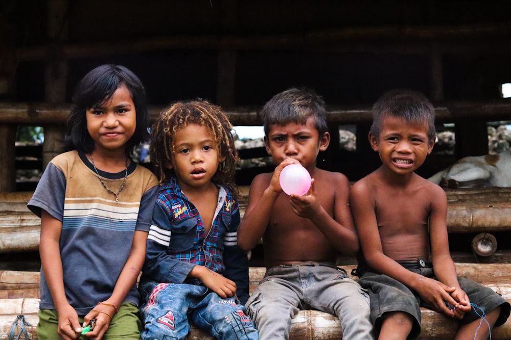 a group of young children sitting on top of a wooden bench