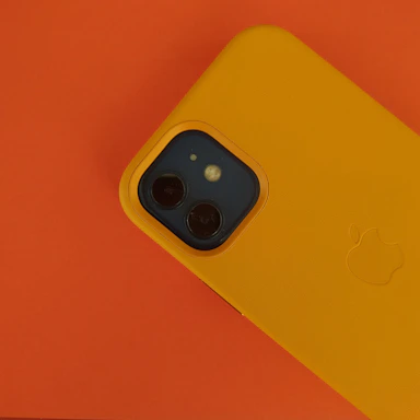 A friendly customer service representative holding a smartphone with a bright orange background.