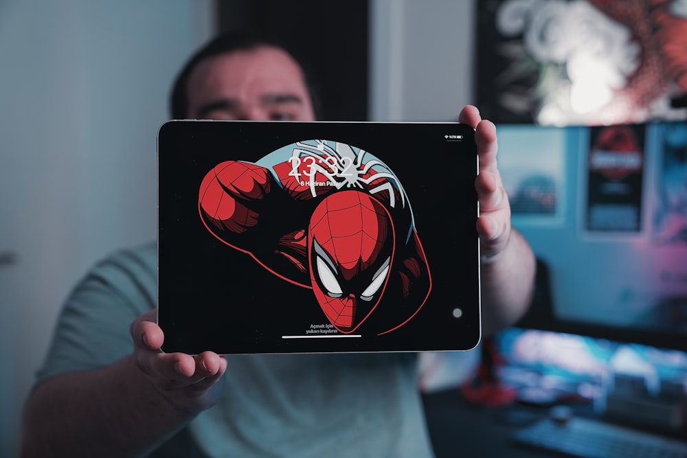 a man holding up a tablet with a spiderman sticker on it